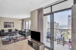 Bright open-plan lounge with private balcony, ocean views, floor-to-ceiling windows and comfortable seating in a modern Cape Town CBD apartment.