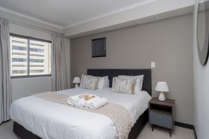 Spacious king-size bedroom with luxury bedding, natural light, built-in storage and city views in a modern Cape Town CBD apartment.