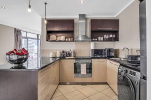 Fully equipped modern kitchen with oven, dishwasher, washing machine, Smeg appliances, Philips Airfryer and breakfast bar in Cape Town CBD apartment.