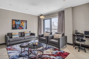 Modern lounge area with comfortable seating, workspace, city views and natural light in a luxury Cape Town CBD apartment.