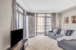 Spacious second lounge with sleeper sofa, smart TV, floor-to-ceiling windows and city views in a modern Cape Town CBD apartment.