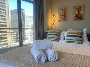 Second lounge with sleeper couch, city skyline views, floor-to-ceiling windows and mountain backdrop in Cape Town CBD apartment.